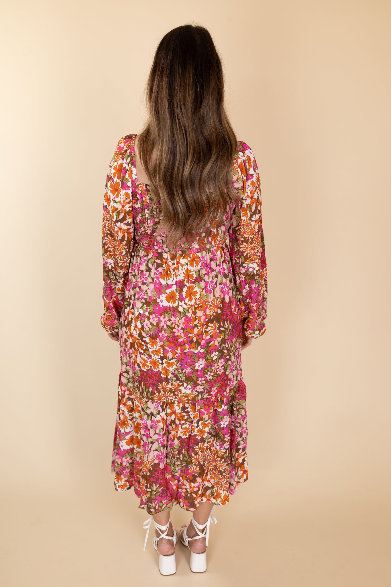 Back view of Stella Floral Smocked Dress with billowy long sleeves, floral print in various browns, pinks, and oranges, and a smocked bodice.