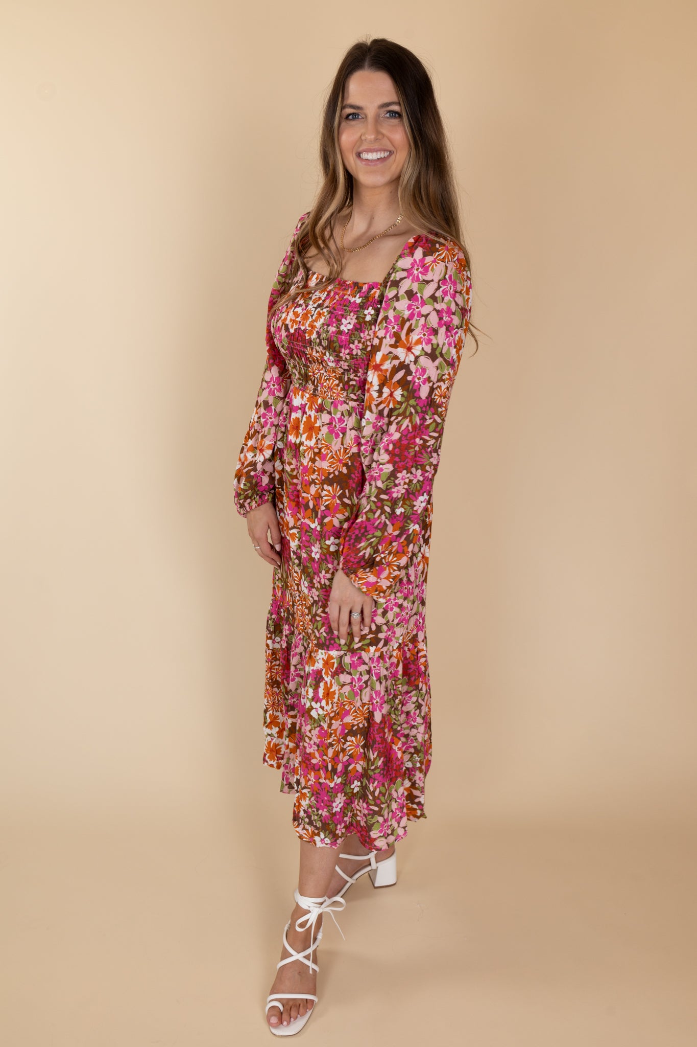Side detail view of Stella Floral Smocked Dress with billowy long sleeves, floral print in various browns, pinks, and oranges, and a smocked bodice.
