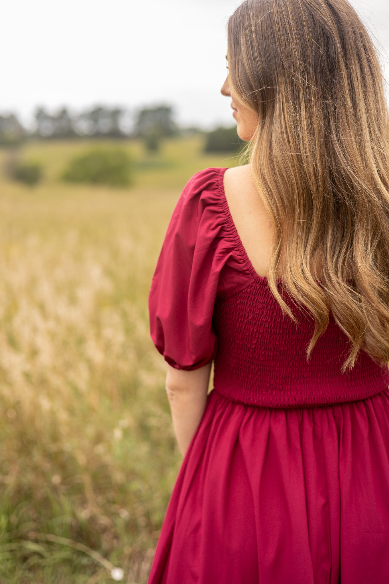 back view of berry colored puff sleeve dress with smocked bodice on back