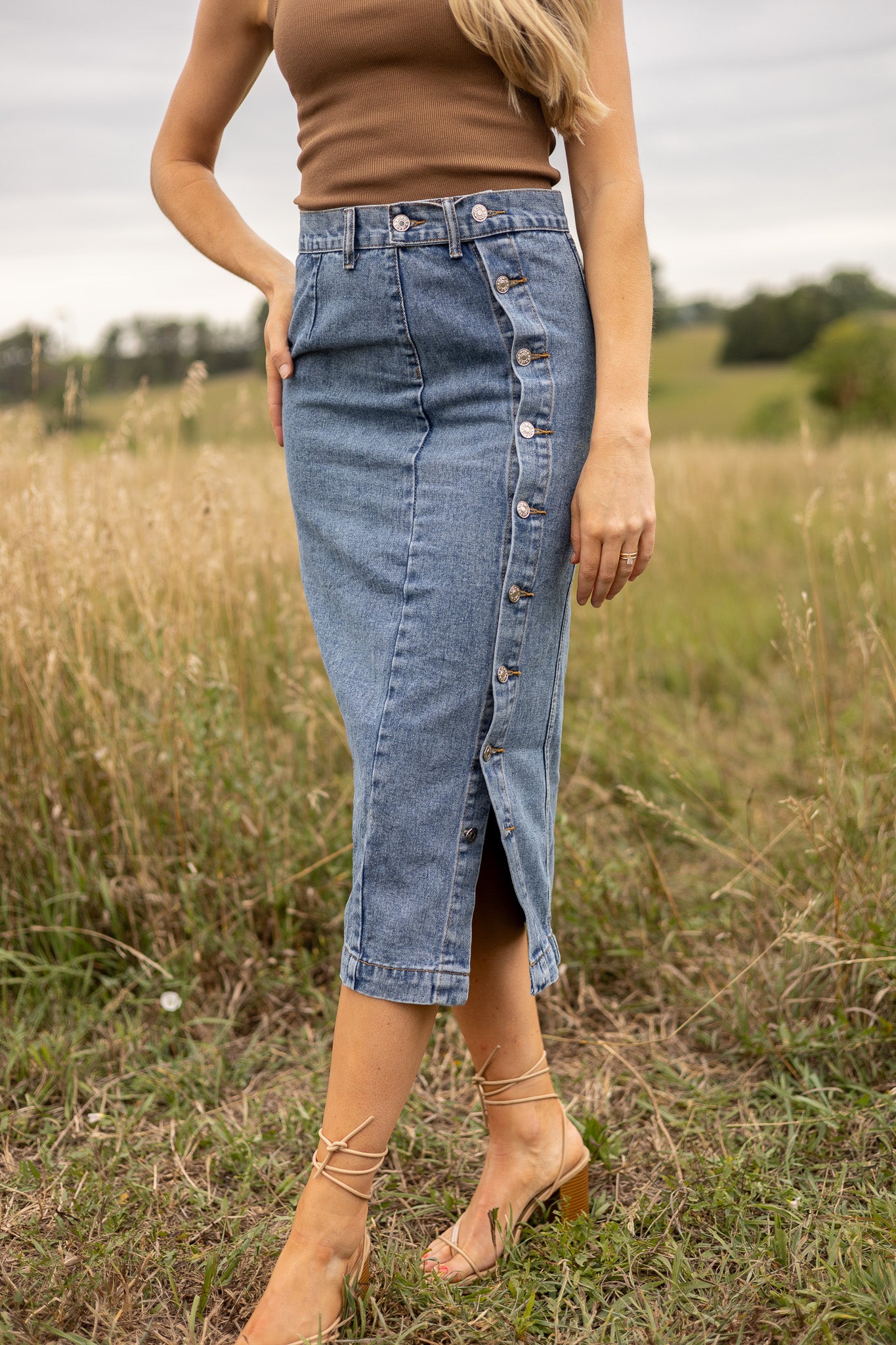 side front view of medium wash denim midi skirt with side buttons all the way down