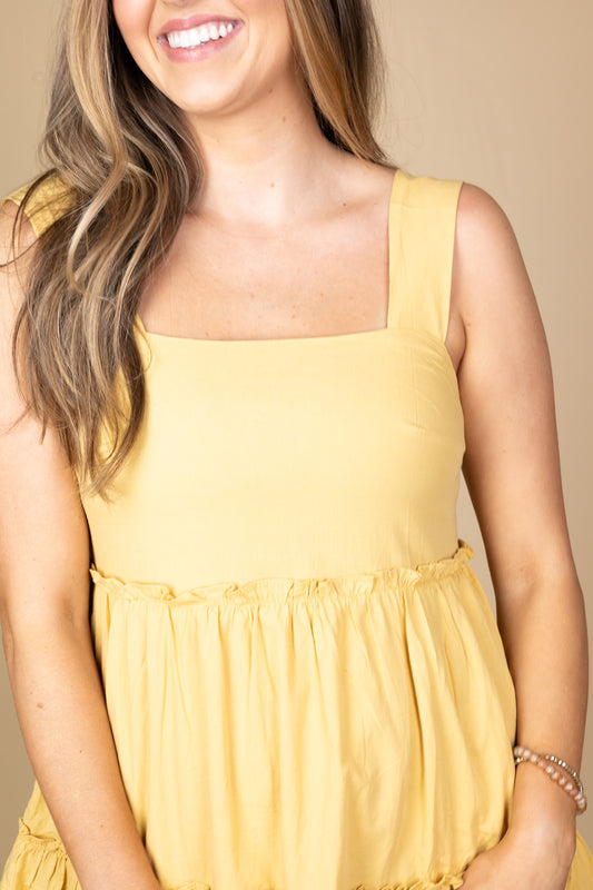close up Sunny Days Ahead Sun Dress in muted mustard yellow with tiered ruffle detailing, thick straps, and rouched elastic backing