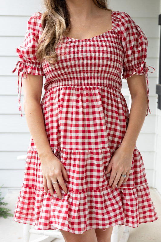 close up view Riley Red Gingham Smocked Dress with puff sleeves, bow detail, pockets, and smocked bodice in red and cream gingham