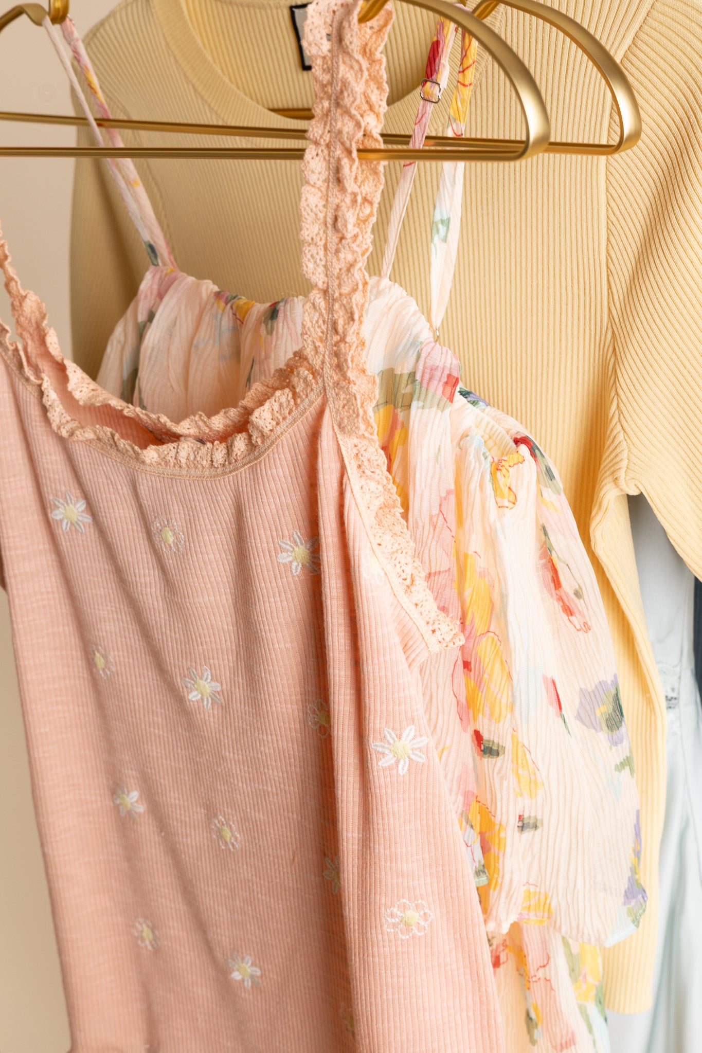 hanging up Daisy Lane Lace Tank in peachy pink with embroidered daisies, lace trim, soft heathered fabric, and fitted silhouette