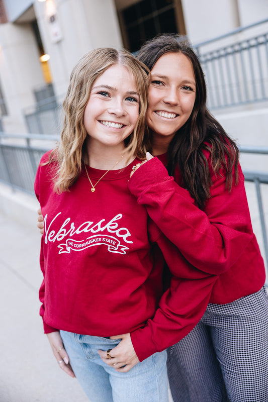 Deep red Nebraska crewneck sweatshirt with white script print, soft fabric, and relaxed fit for game day or casual wear