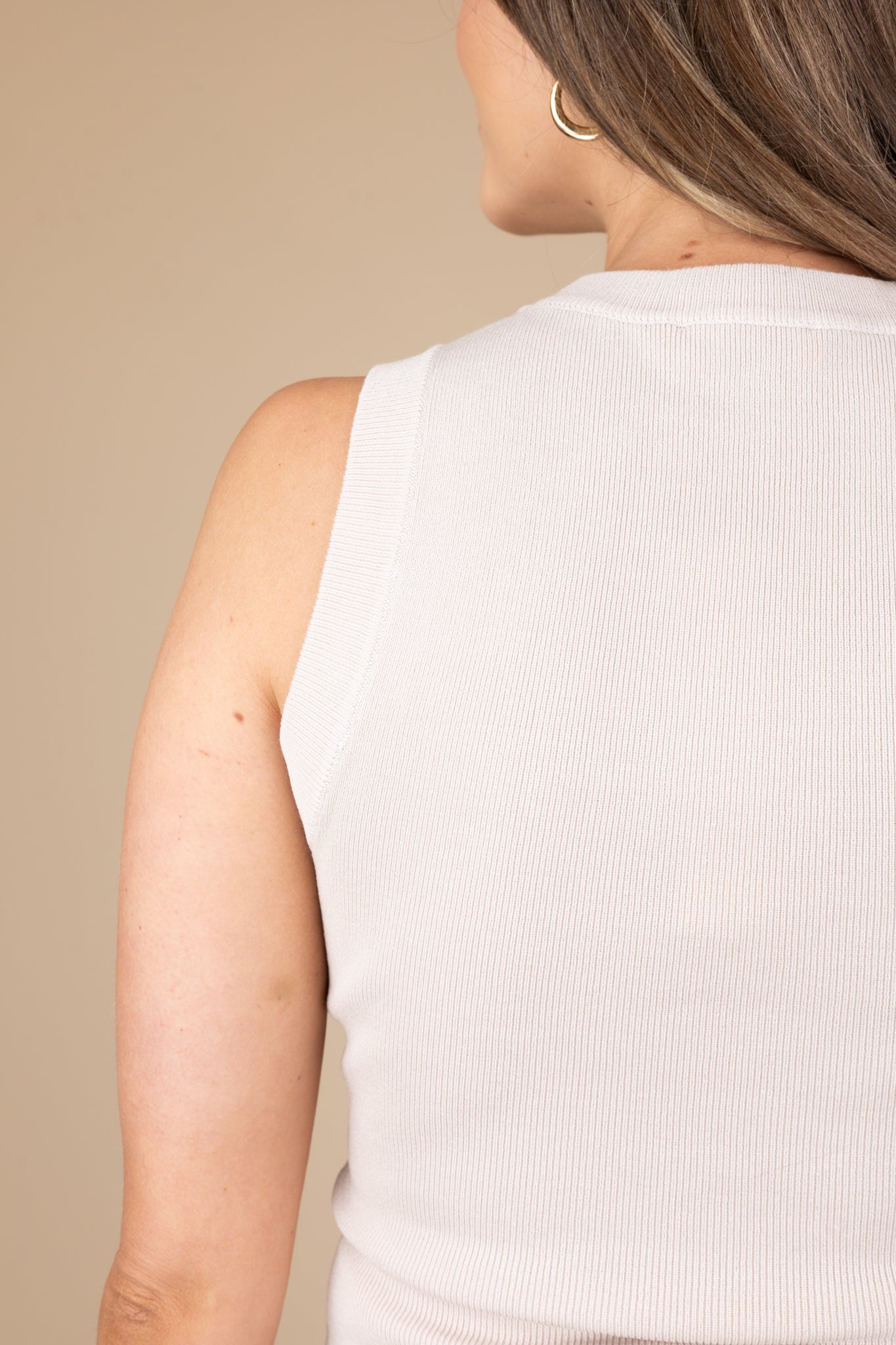 back detail of Cream high neck sleeveless knit top with ribbed material, offering a soft and stylish fit.