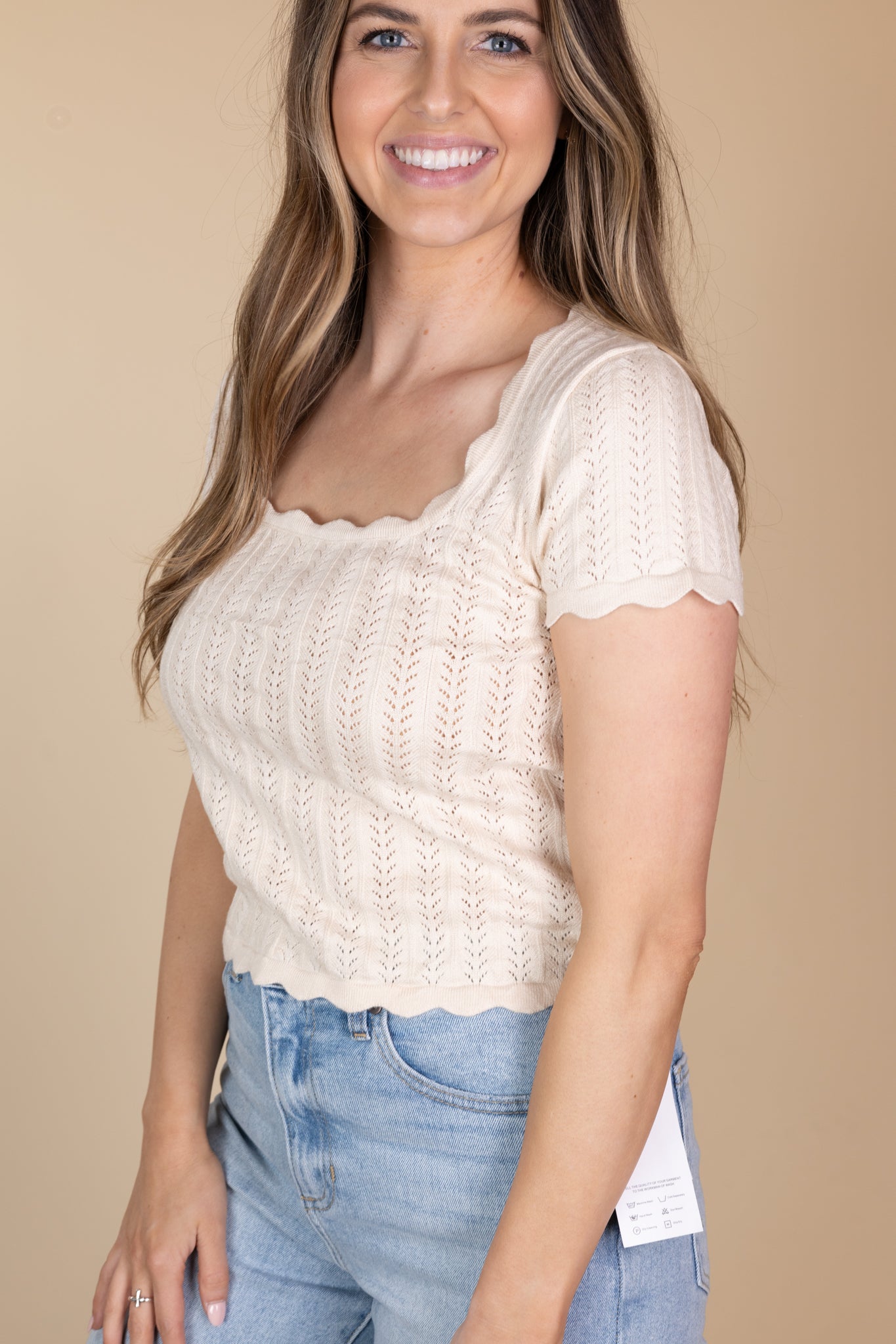 Side view of Remi Scalloped Knit Top in cream with a square neckline, scalloped trim, and fitted design. Ideal for adding a feminine touch to your look.