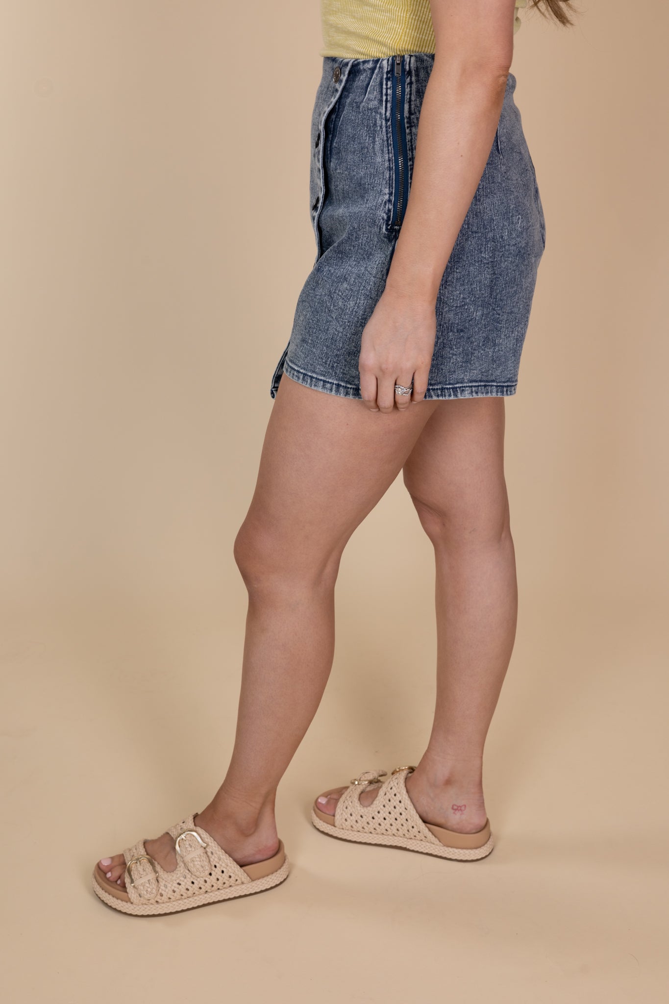 side view of Dark acid wash Blakely skort with a high rise, side buttons, and zipper closure, featuring a skirt front and shorts underneath.