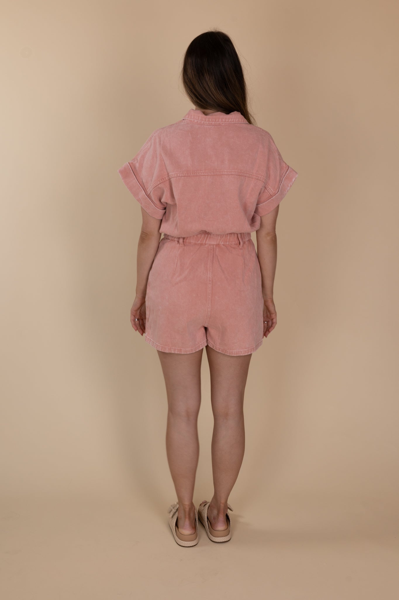 back view of Relaxed Pink Denim Romper with snap button front and zipper closures. Pink color with a relaxed fit. 