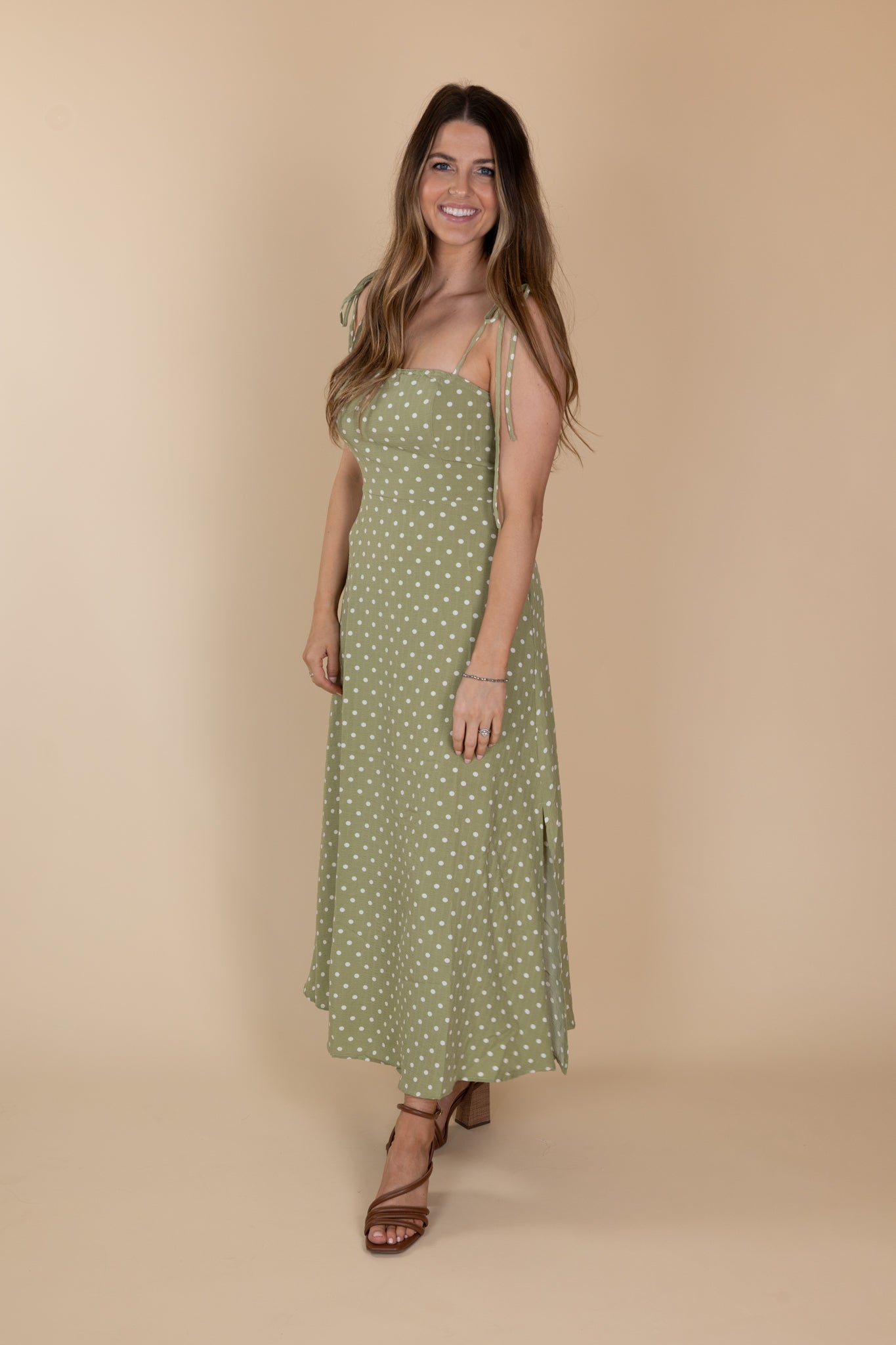 Side view of Willow Classic Polka Midi Dress in light green with white polka dots, tie adjustable straps, fitted chest/torso, loose skirt, and midi length. True to size fit.