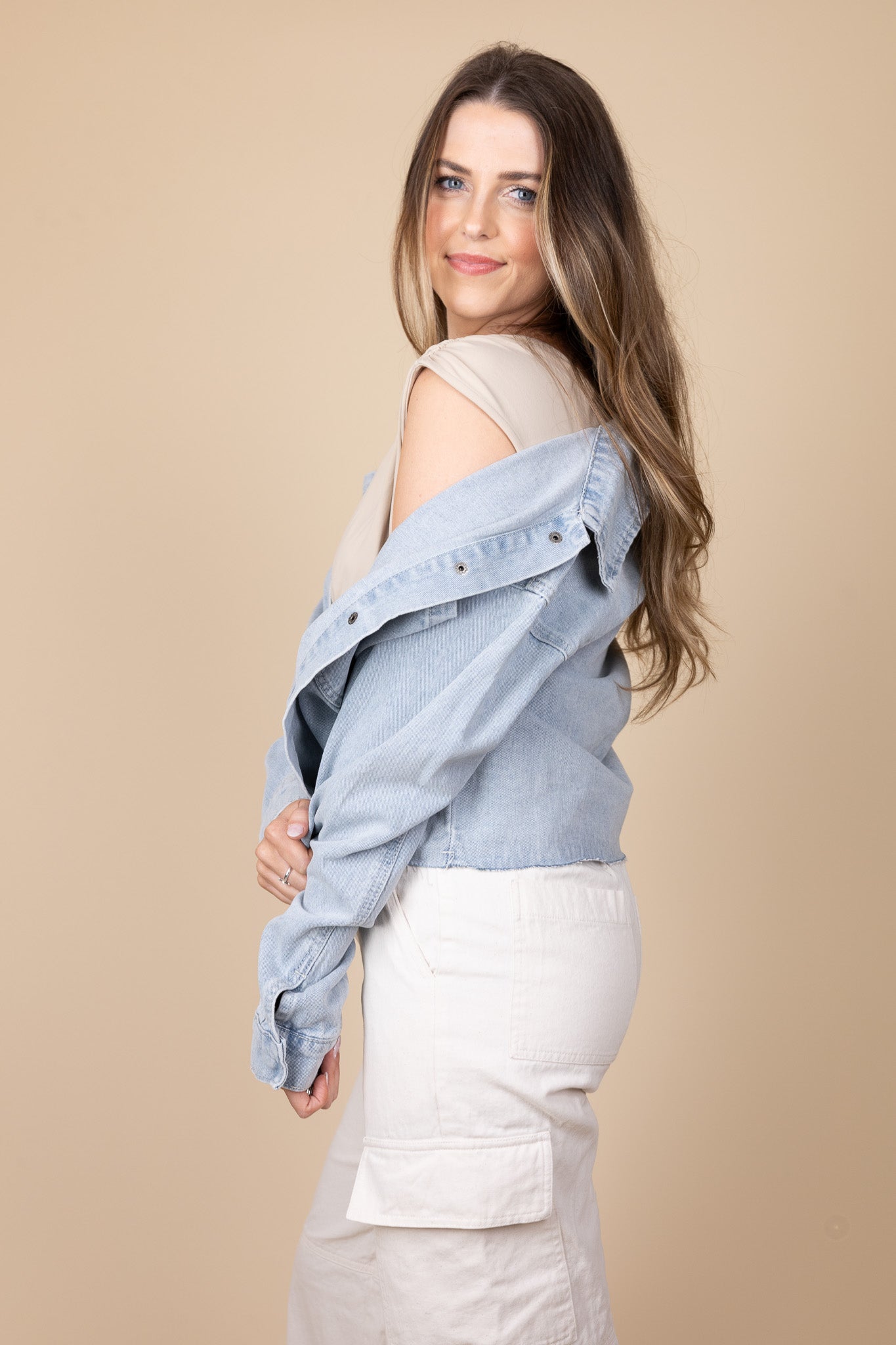 off shoulder view of Zoey Lightweight Denim Jacket in light wash color with snap button closure, raw hem, and oversized fit, styled for any season.