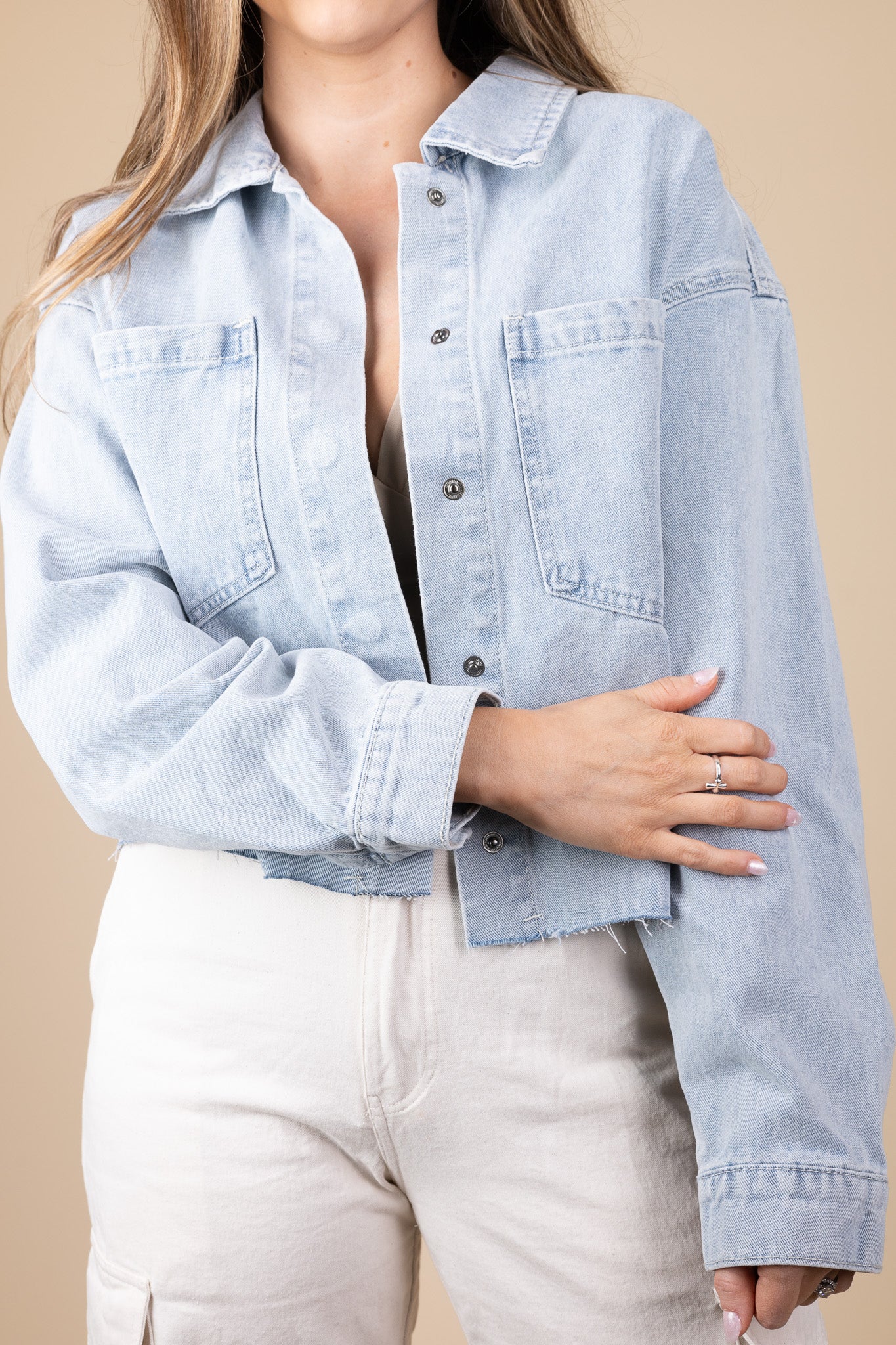 arm length detail view of Zoey Lightweight Denim Jacket in light wash color with snap button closure, raw hem, and oversized fit, styled for any season.