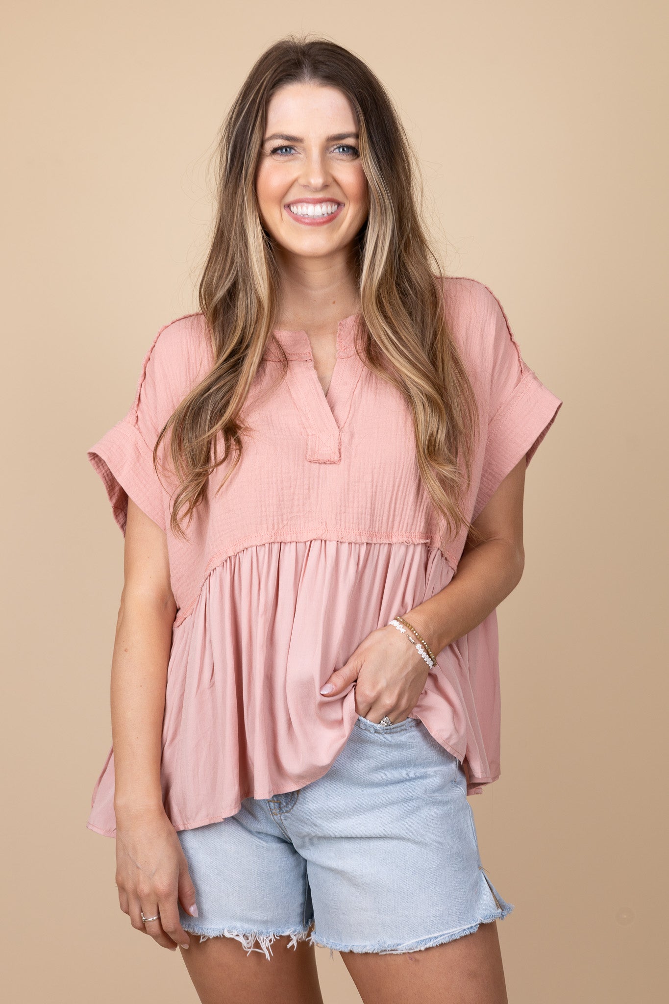 detailed view of bradyn Flowy V Neck Top in pink with v-neck, raw hem detailing, and drop shoulder design. Flowy and below waist length.