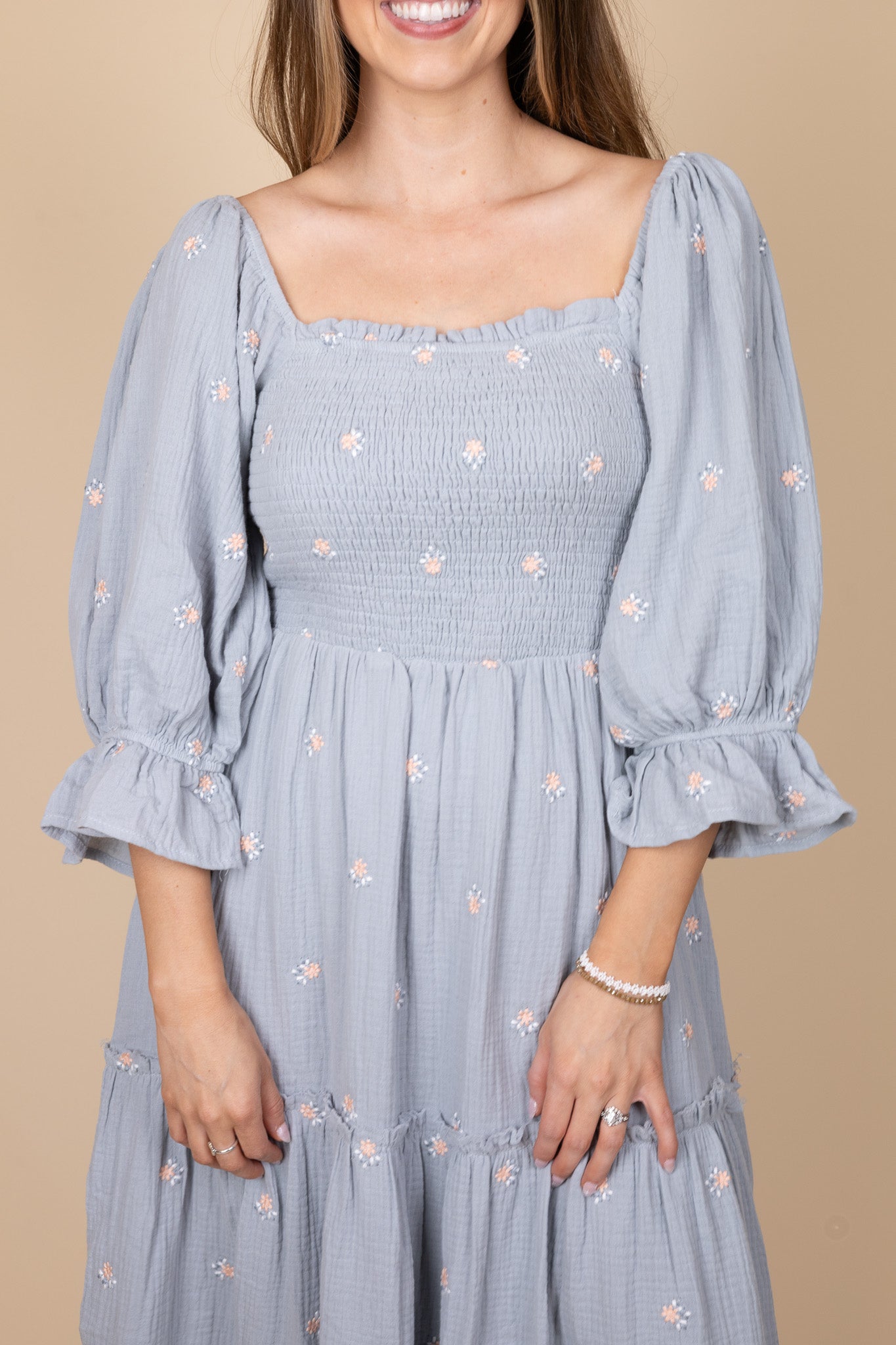 front view of Emma Floral Midi Dress with a flowy silhouette, featuring a light blue base with pink floral print, ruffle hem sleeves, and smocking through the torso. Perfect for various occasions, this midi-length dress offers a true-to-size fit.