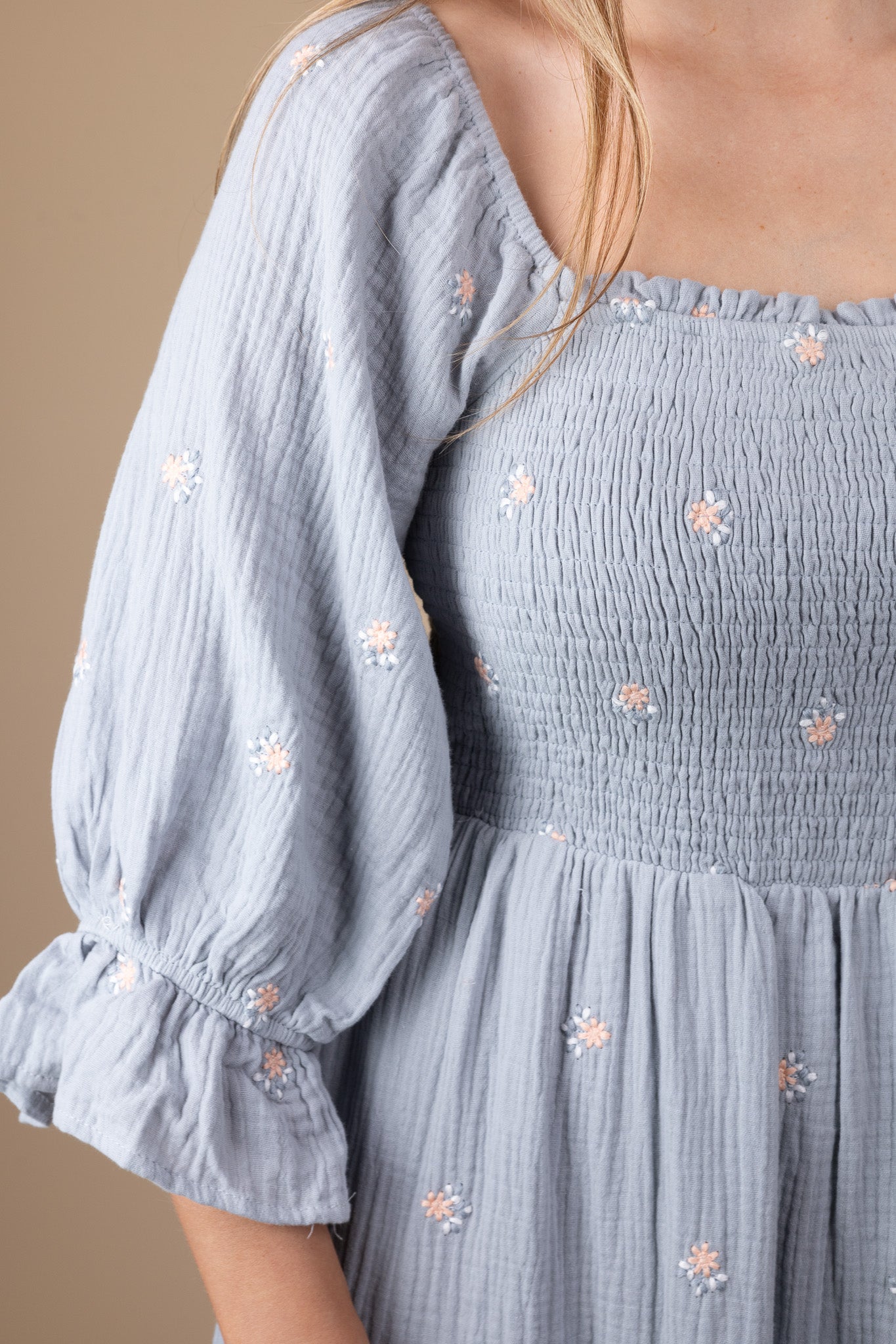 shoulder detail of Emma Floral Midi Dress with a flowy silhouette, featuring a light blue base with pink floral print, ruffle hem sleeves, and smocking through the torso. Perfect for various occasions, this midi-length dress offers a true-to-size fit.