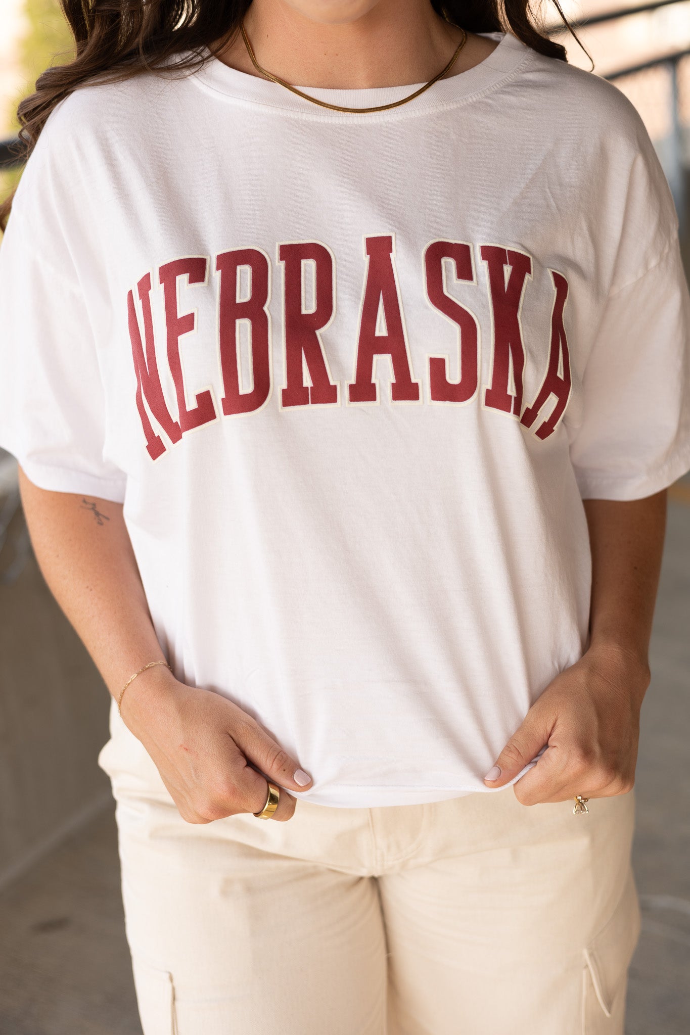 full waist length view of Nebraska tee, vintage red font, boxy fit, white in color paired with jean skort