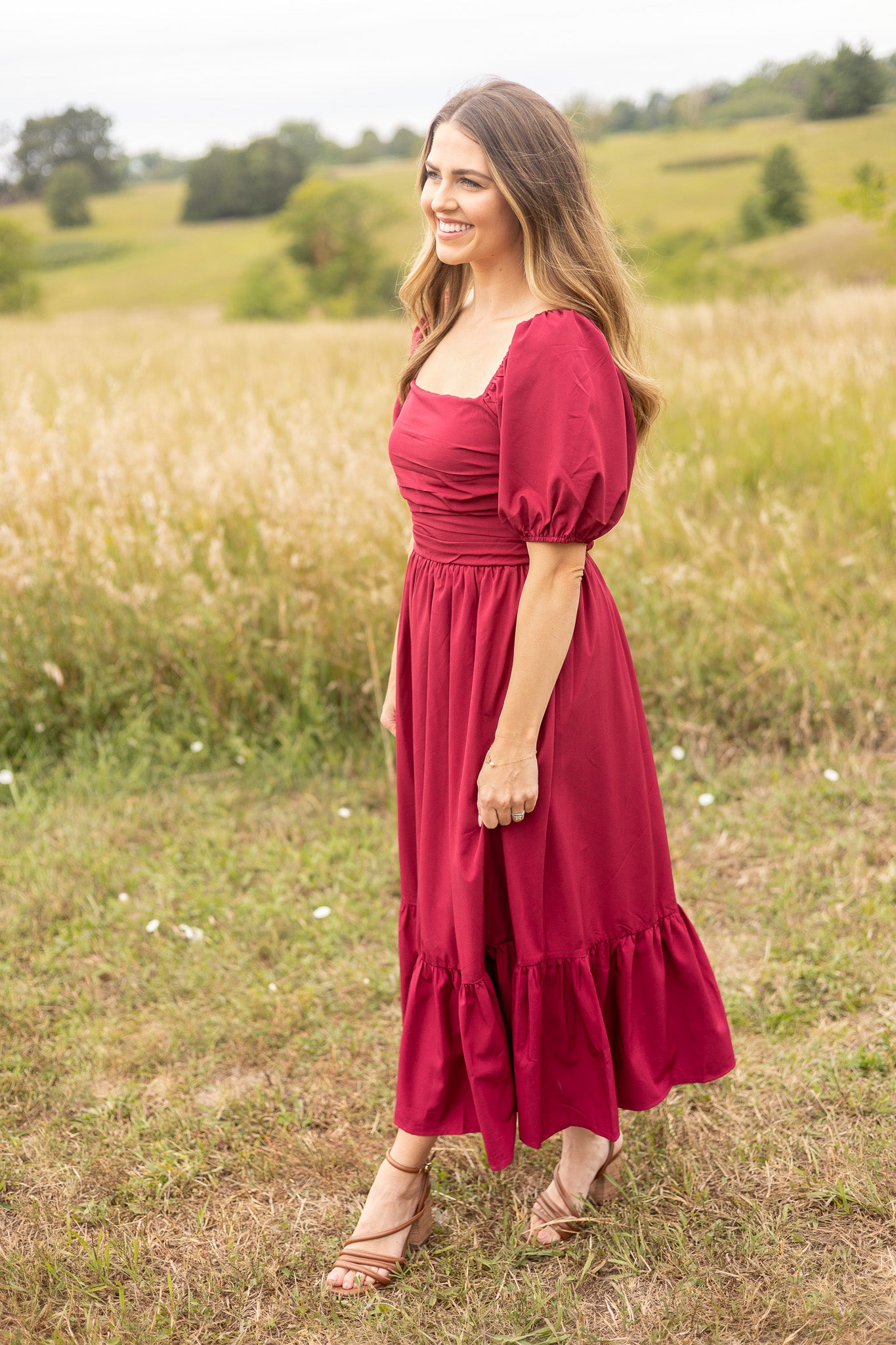 side view of berry colored puff sleeve dress with ruched bodice and ruffle trim on skirt, maxi length