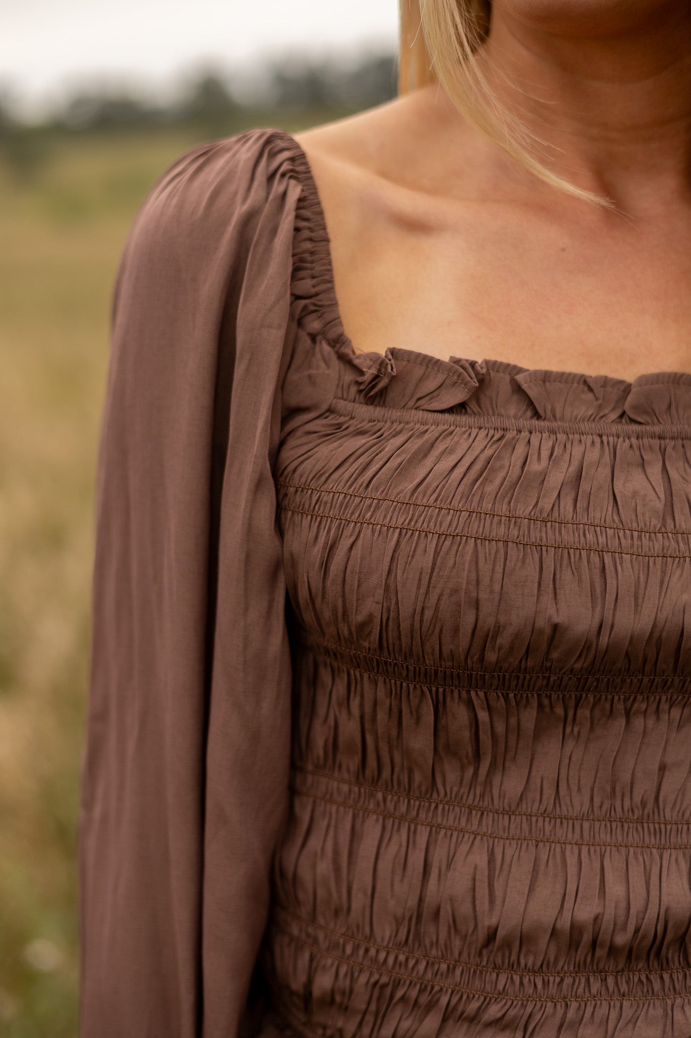 shoulder view of brown belle sleeve top smocked bodice with ruffle trim elastic trim on shoulder of sleeve and wrist