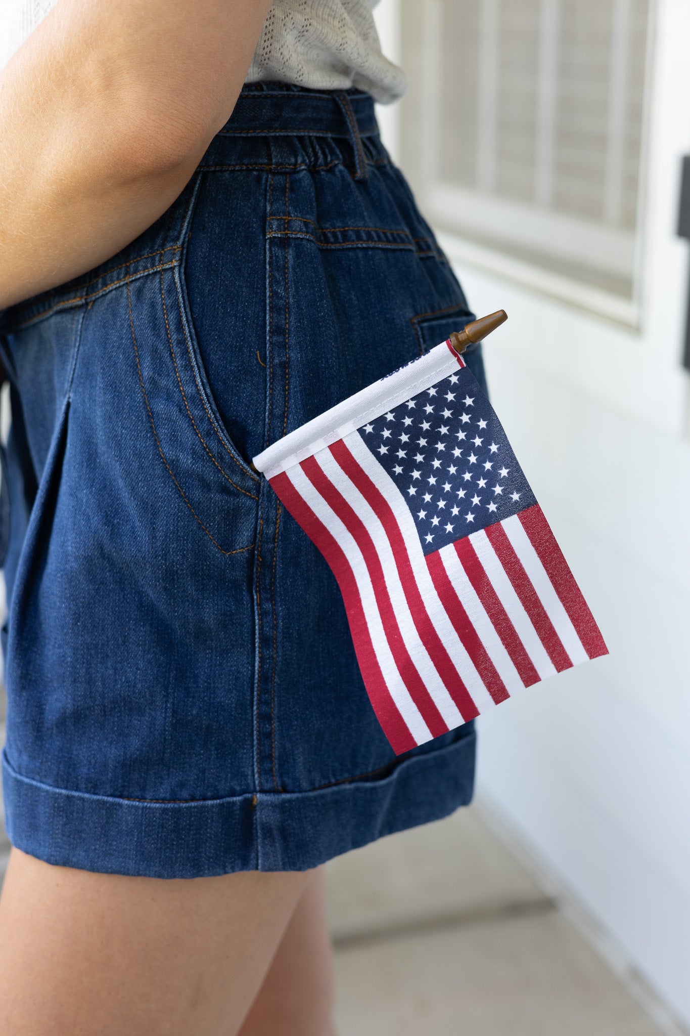 flag in pocket Avery Pleated Denim Shorts in dark wash with tie waist, pleated front, elastic waistband, and cuffed hem

