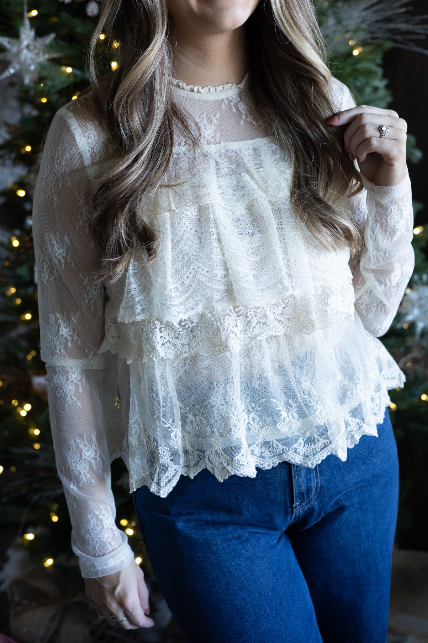 Person wearing a lace top with a Christmas tree in the background
